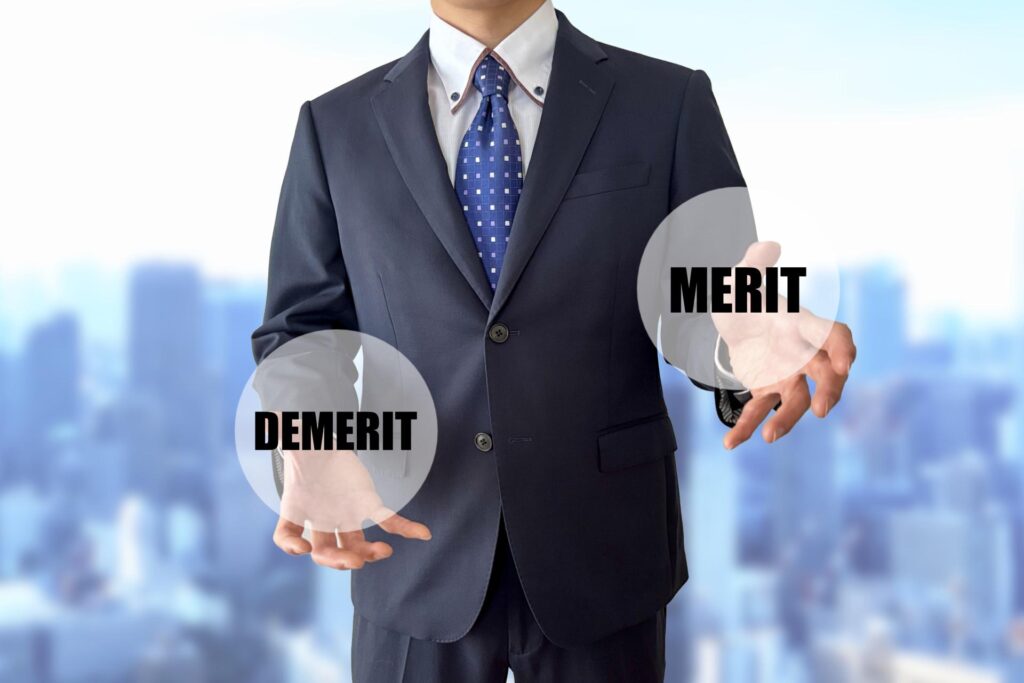 「MERIT」「DEMERIT」の球体を持つスーツ姿の人物の写真