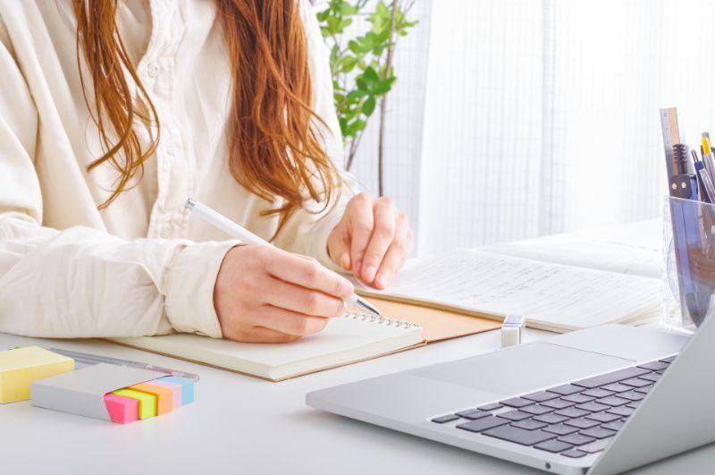 ノートパソコンを使いながら英語学習の勉強をする女性の画像